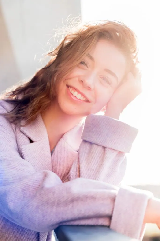 girl with brown hair in grey sweater smiling