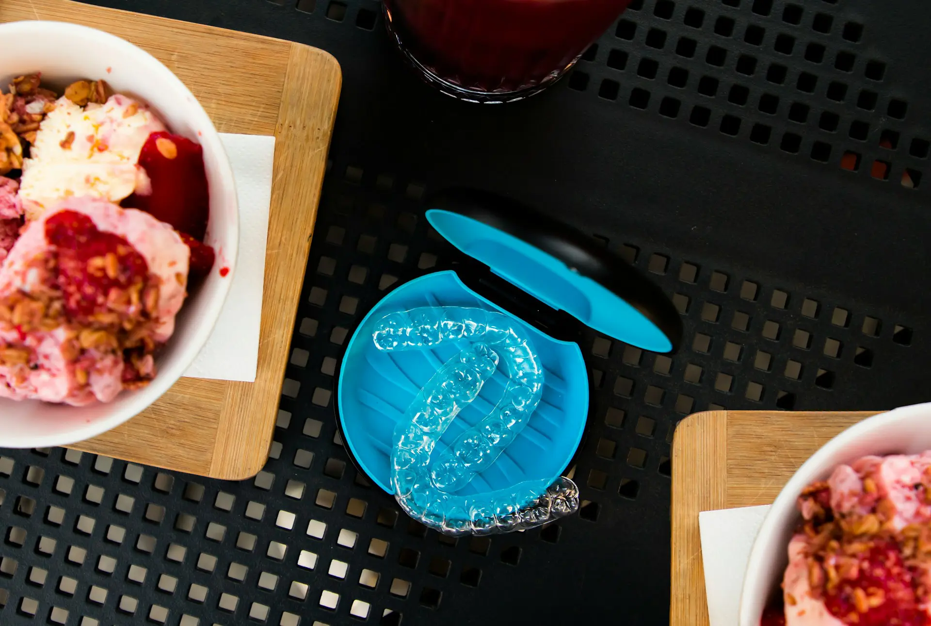 Clear aligners in a black and blue case sitting on a table between two bowls of ice cream