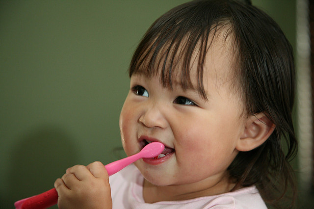 how dental health can impact overall health - toddler holding toothbrush in mouth