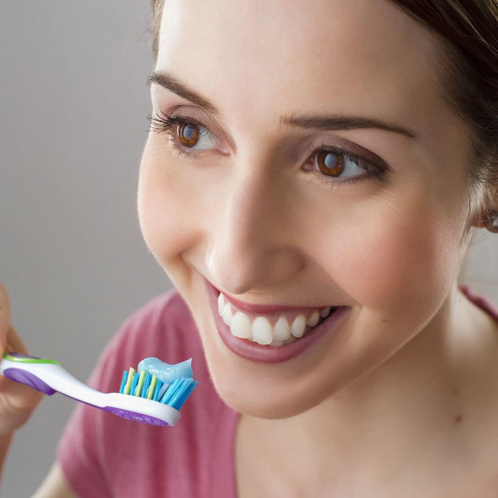 smiling person holding toothbrush near teeth