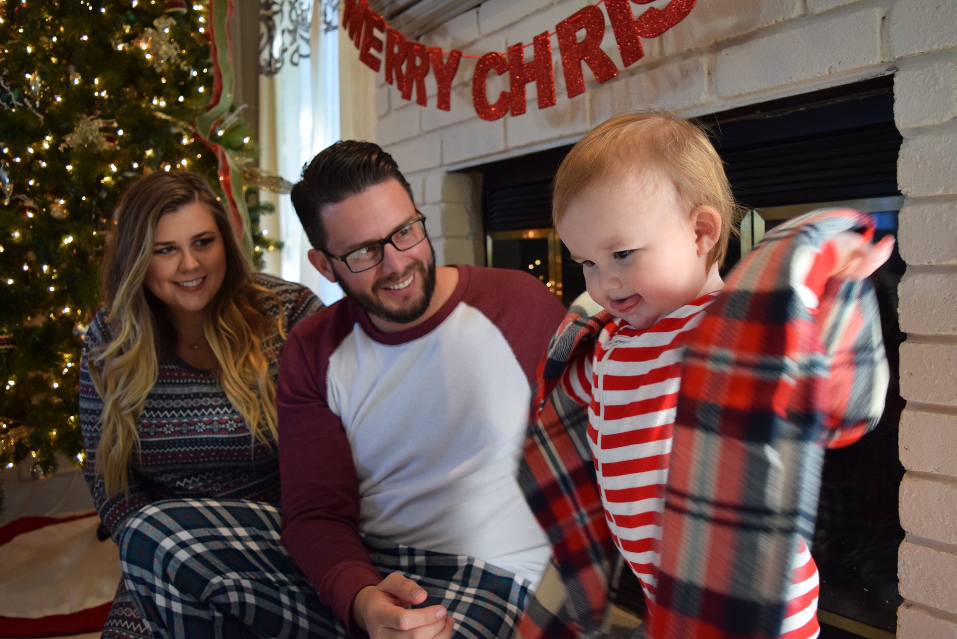 keep your teeth healthy this holiday season - child enjoying new jacket with parents next to Christmas tree