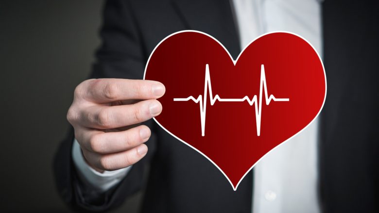 person holding a heart-shaped card with a heartbeat symbol