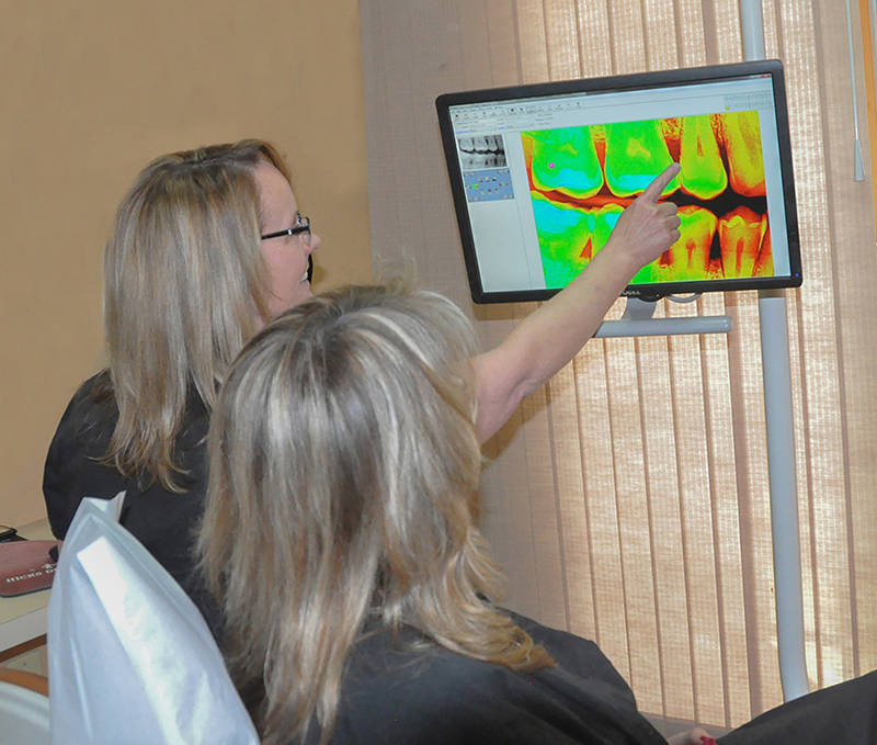 two people looking at a colored xray of teeth