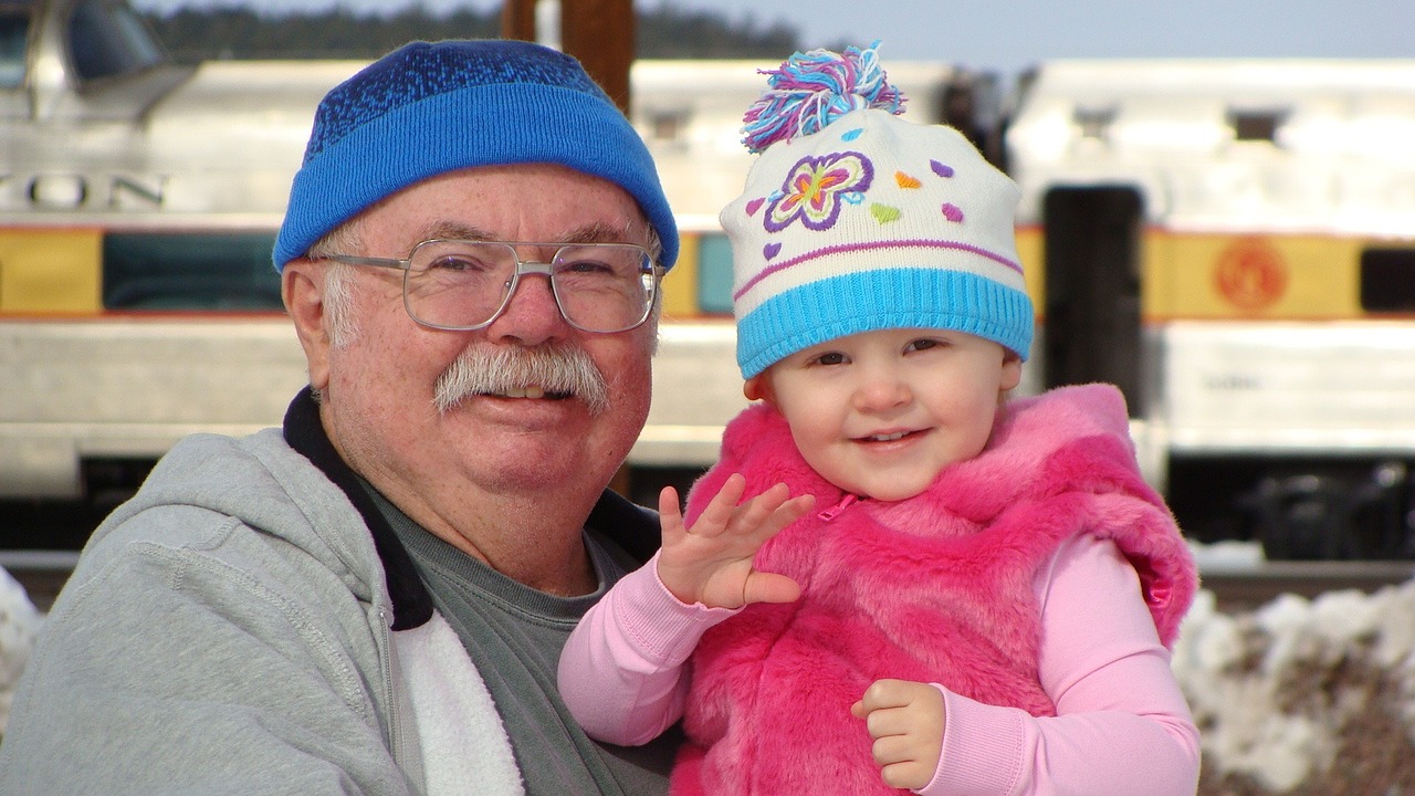Grandpa smiling with granddaughter showing importance of senior dental care