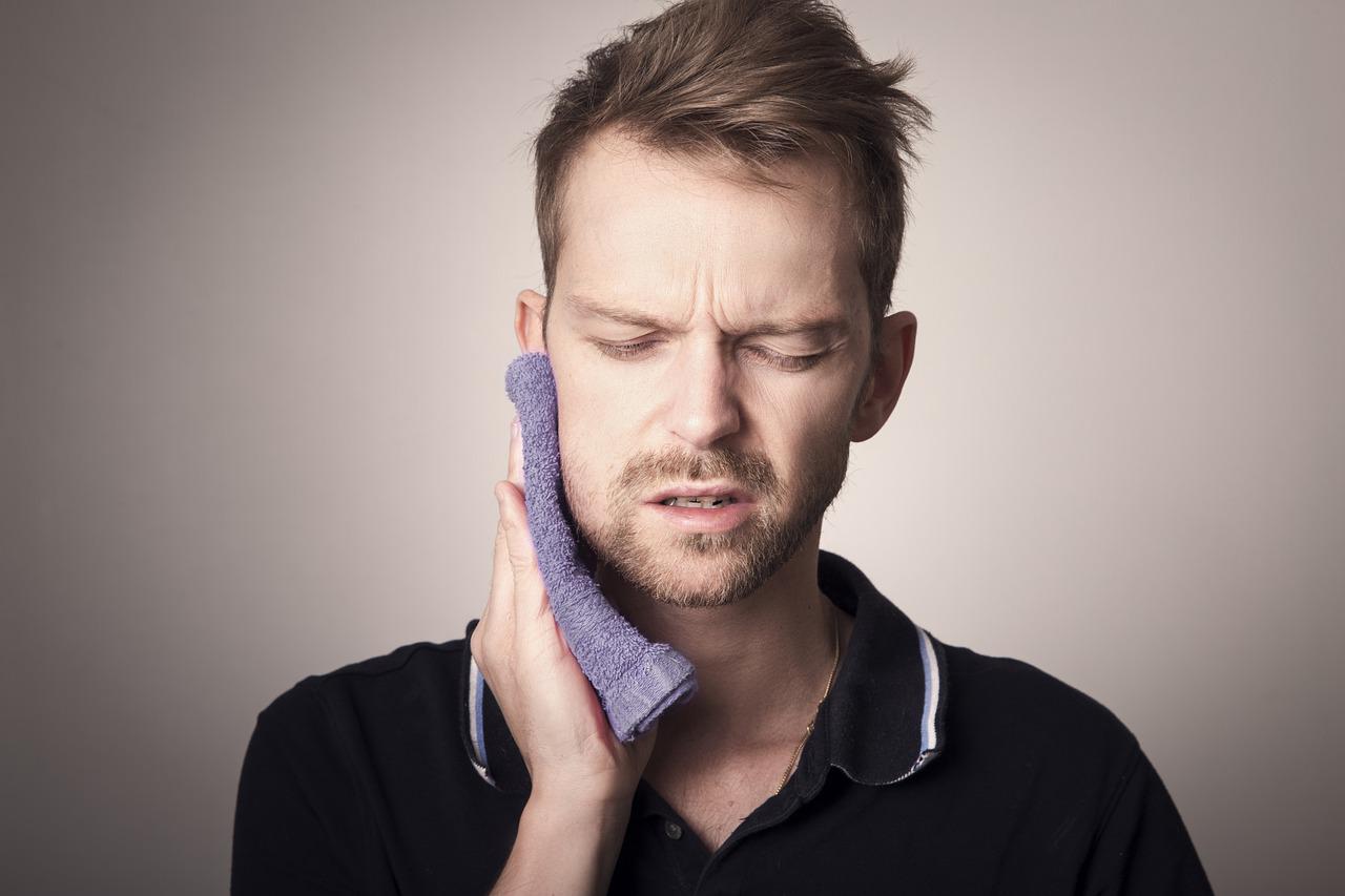 man holding cloth to mouth in pain-what is a dead tooth