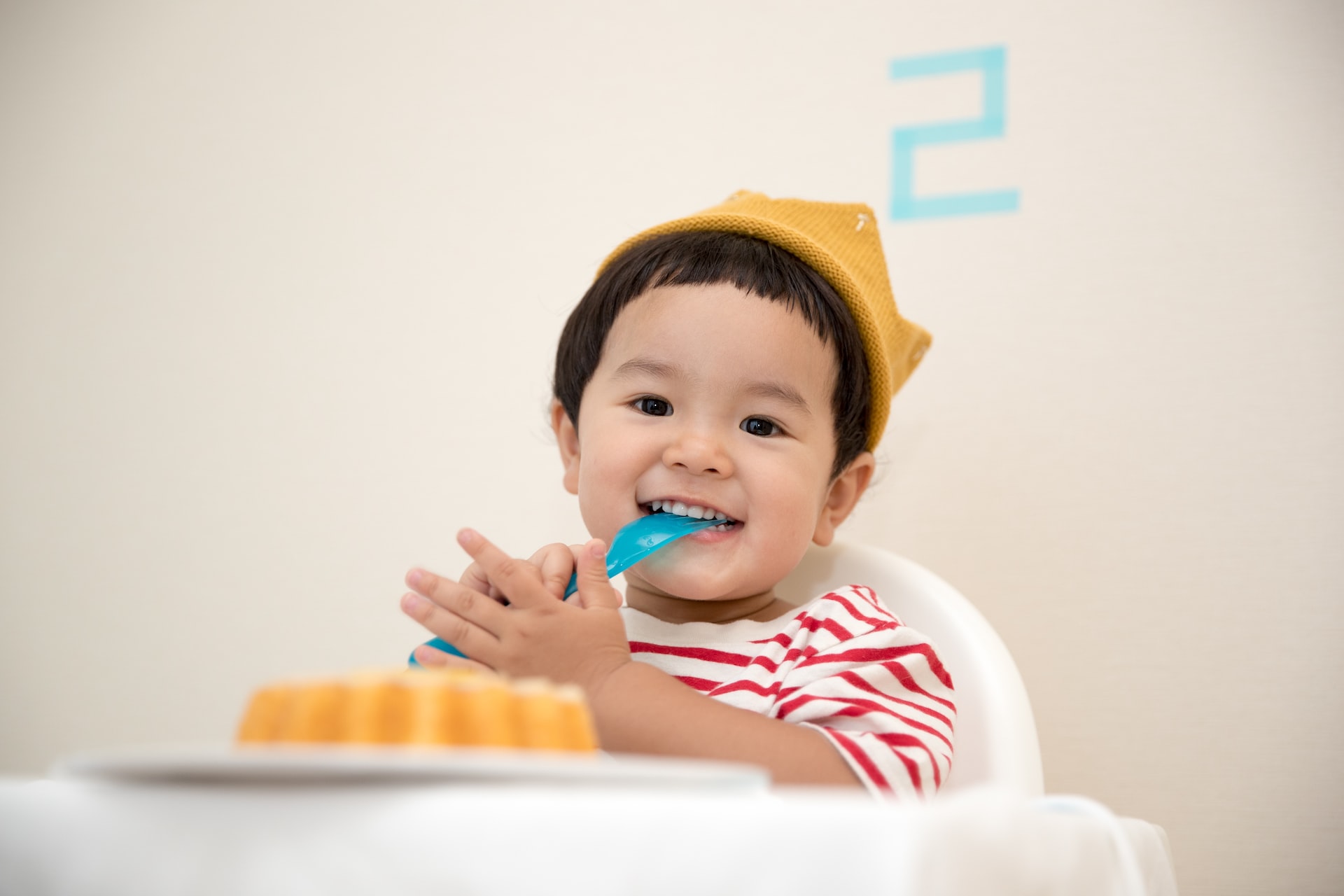 child with a spoon in mouth - when to start brushing your baby's teeth