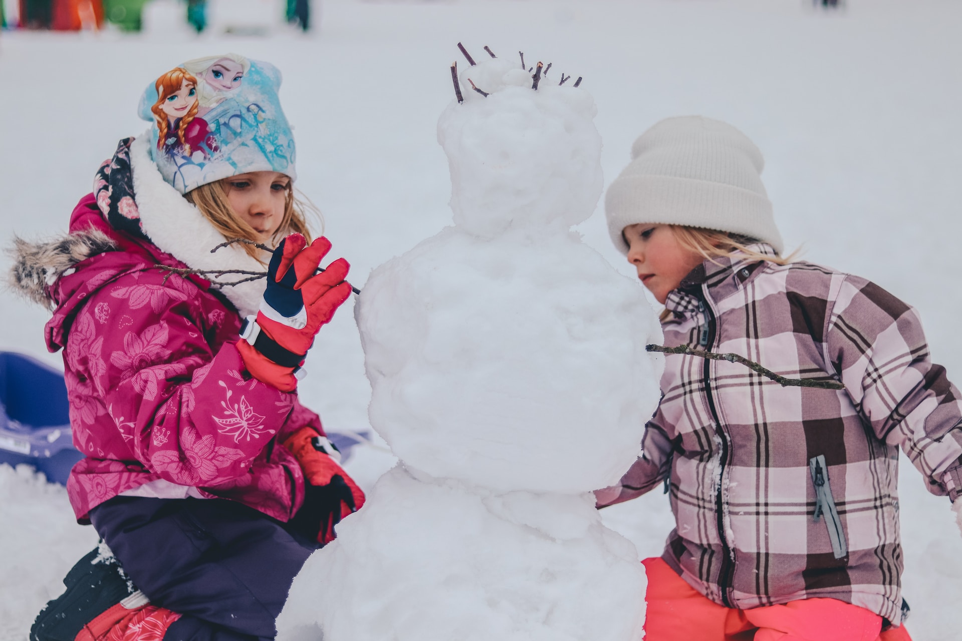 children in warm winter gear building a snowman - 2023 Coat and blanket drive