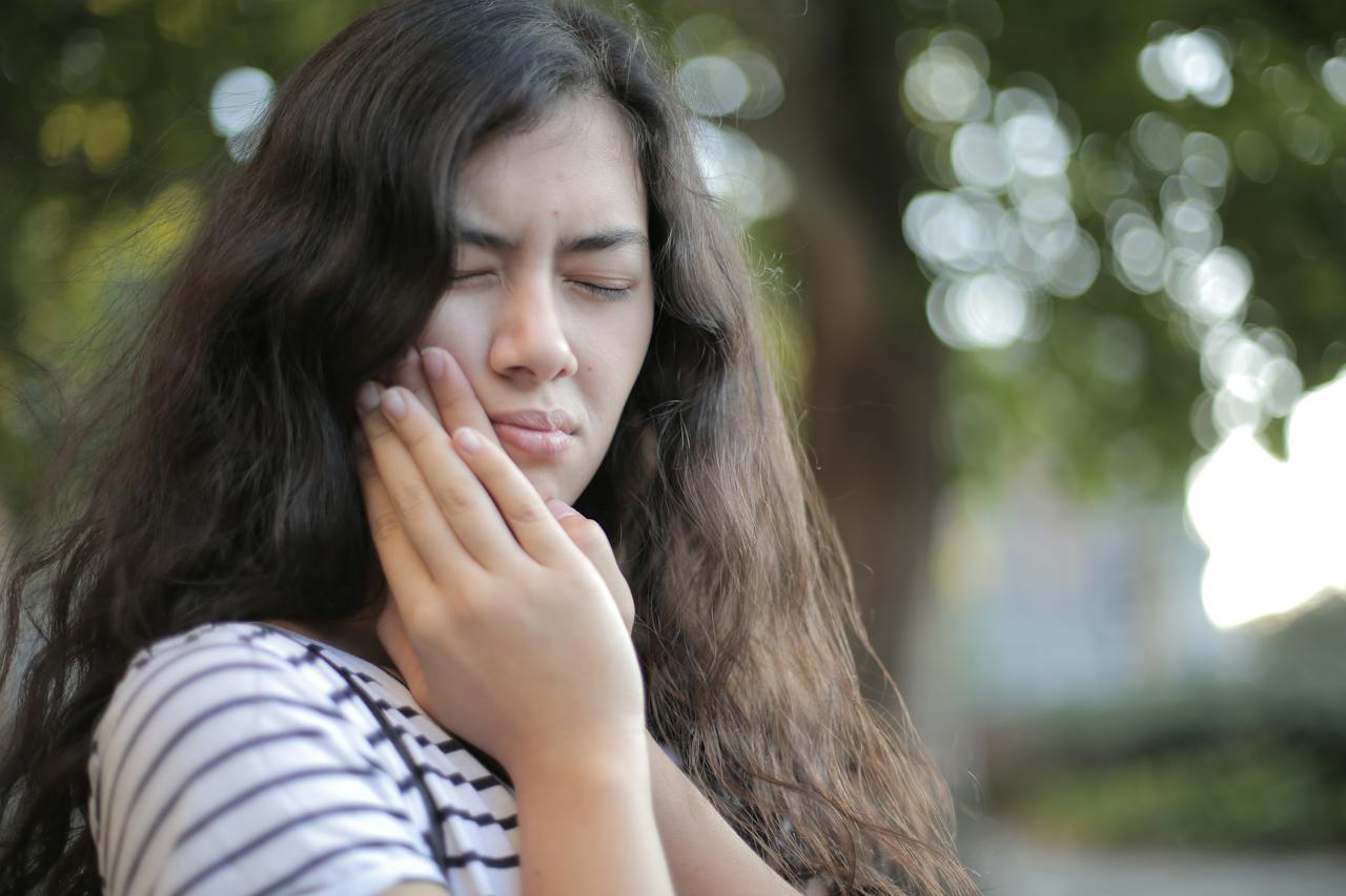 woman whose holding her mouth - are canker sores and cold sores the same