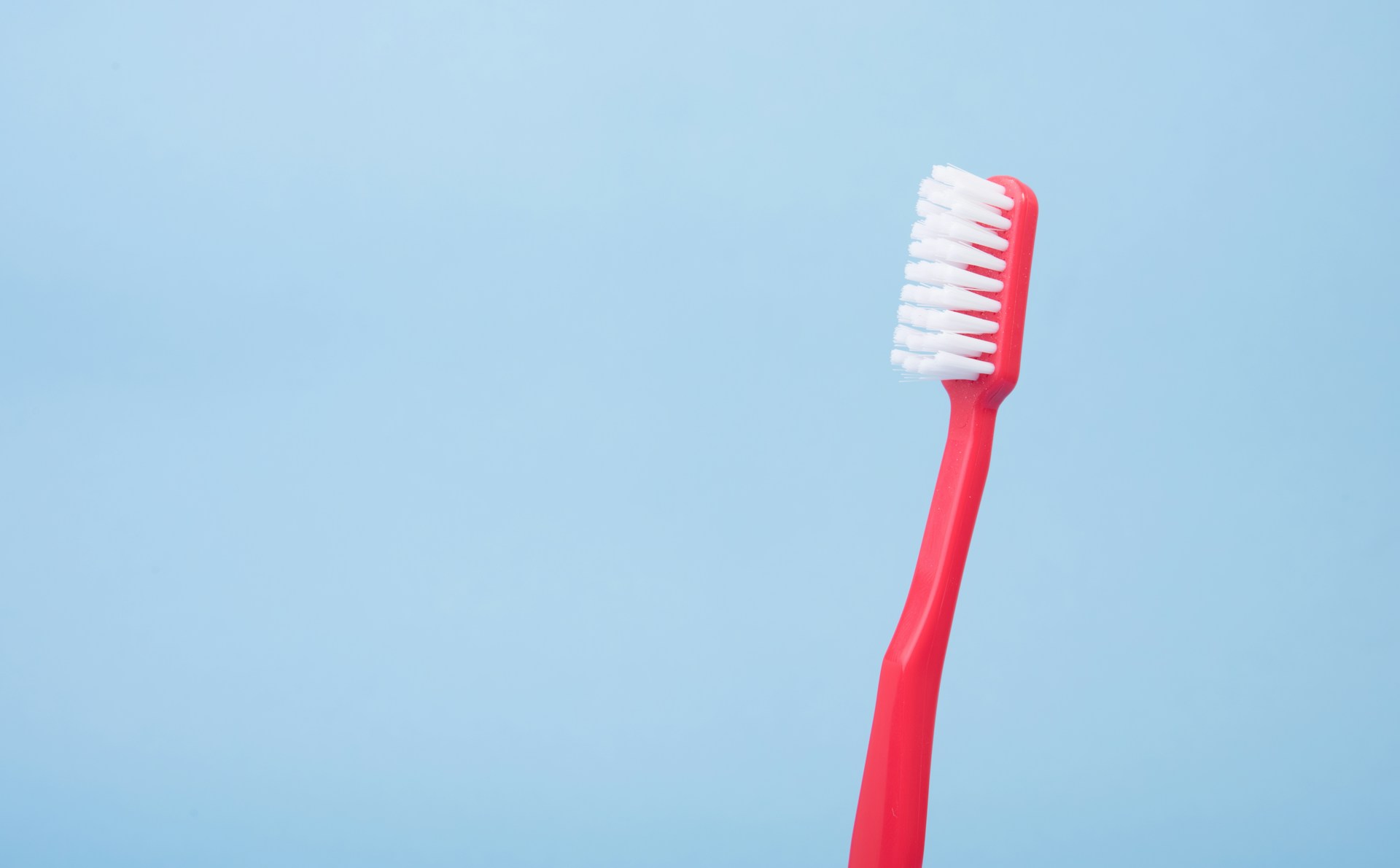 red toothbrush on a blue backdrop- how store a toothbrush